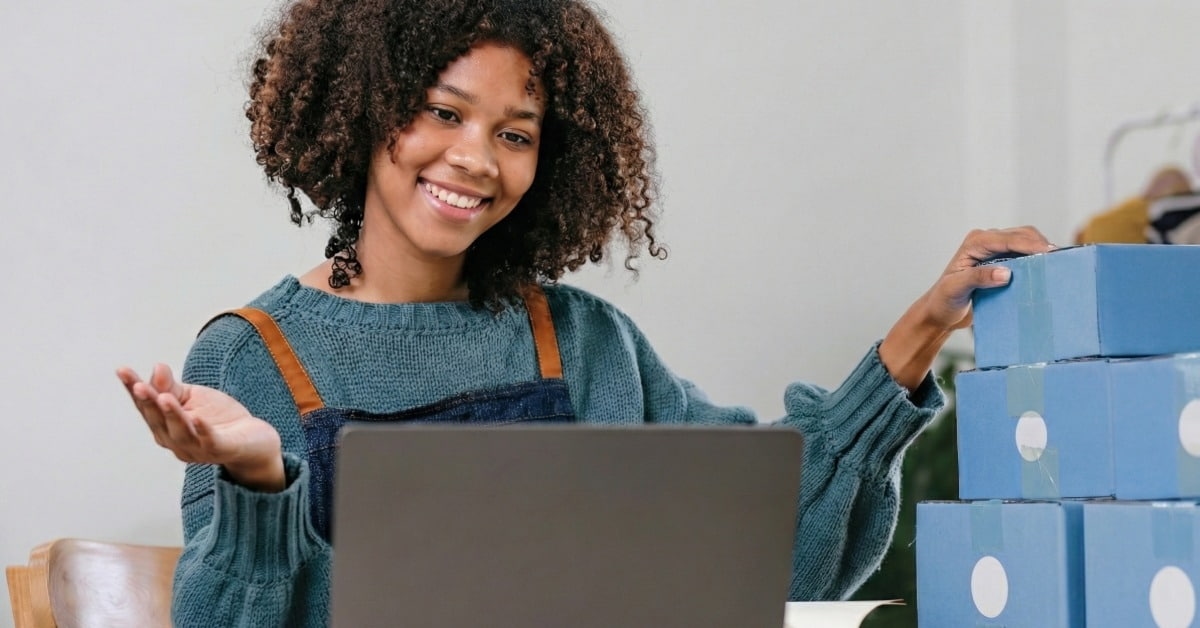 Empreendedora com caixas de envio ao lado do notebook representando como vender na Shopee