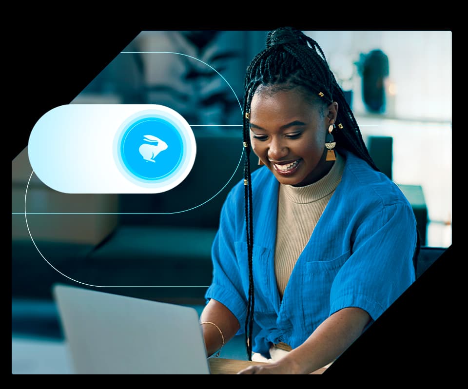 Mulher sorridente usando um notebook em um ambiente interno moderno. Ao lado, há um botão estilizado com o ícone de um coelho branco sobre fundo azul, simbolizando tecnologia e integração com a marca Loggi.